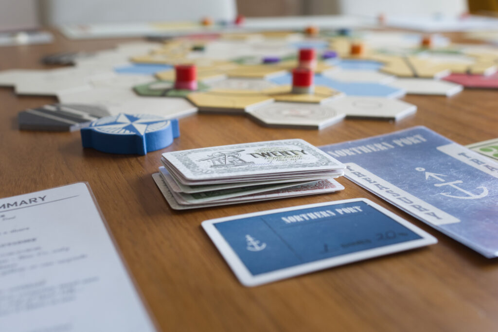 Treasure of a minor company from board game Railways of the Lost Atlas with stack of card money and a company share.