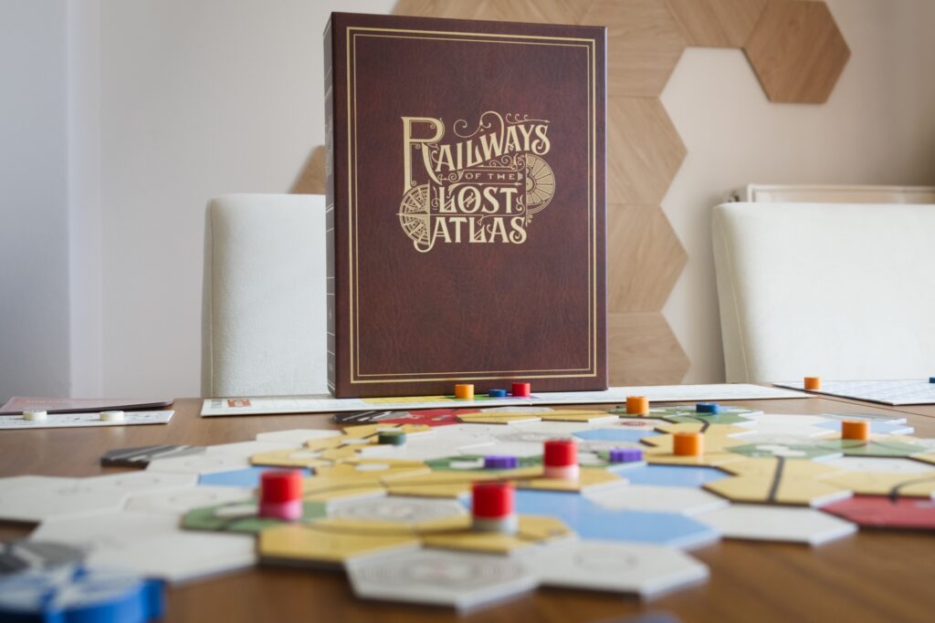 Game box of board game Railways of the Lost Atlas behind map and components