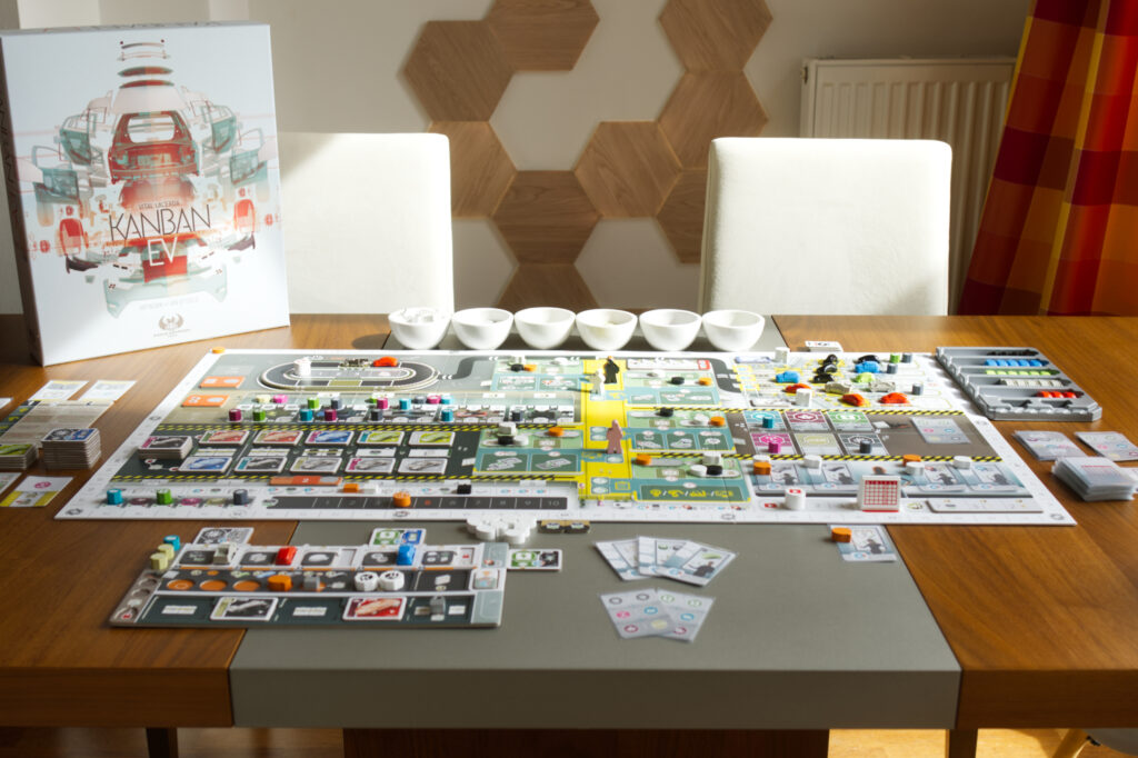 Solo setup of board game Kanban EV with player board in lower left and box cover in upper left.