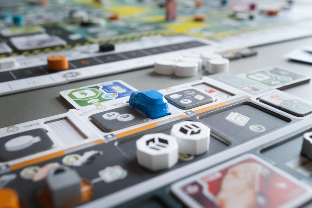 Close up of the player board in Kanban EV with a blue metal car inside a garage